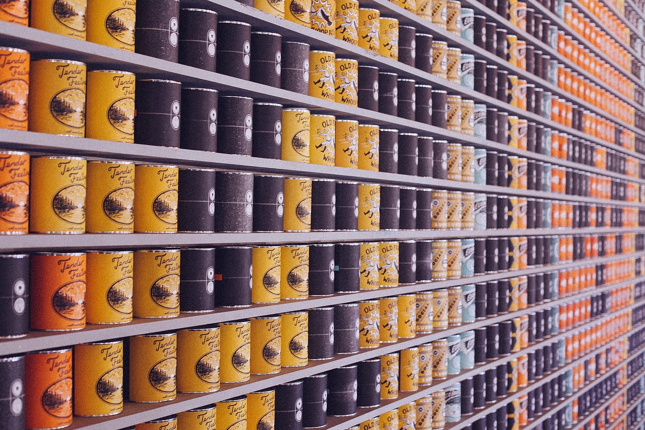 Yellow, dark gray, light blue, and orange canned goods filling up a large shelf. To view the alt text for the other images, first make sure the Image Alt Text Viewer is turned off, then hover over or click on the sentence you want to see the image for, then turn the Image Alt Text Viewer on again.